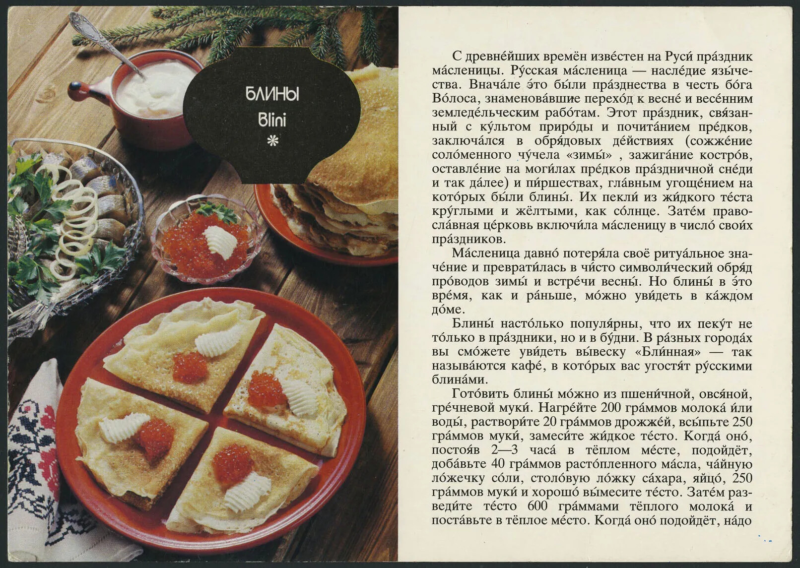A horizontal postcard with a colored photograph on the left and black text on a white background on the right. All of the text is written in a different language than English. The photograph has different foods placed on plates of varying sizes. All of the plates sit on a wooden table.
