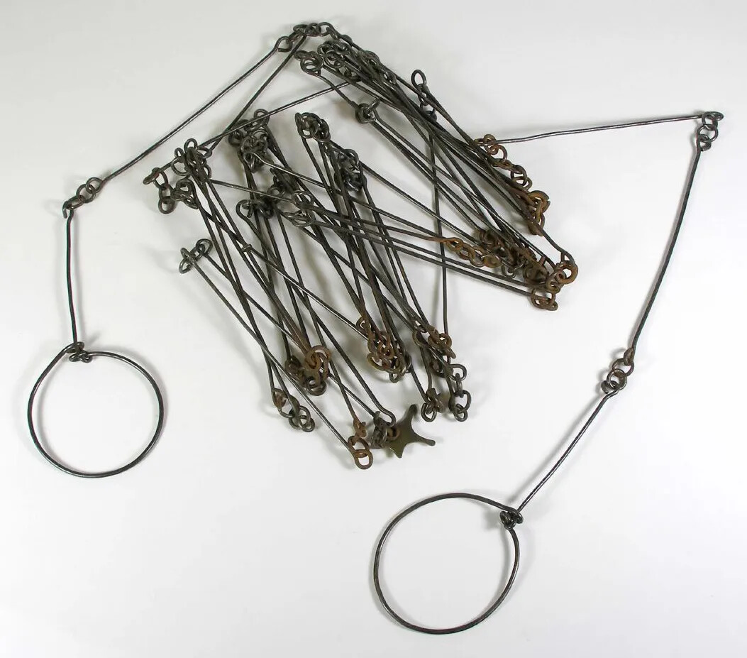 A metal tool with two circles at the ends and several smaller circles holding long strips of metal together in the middle.