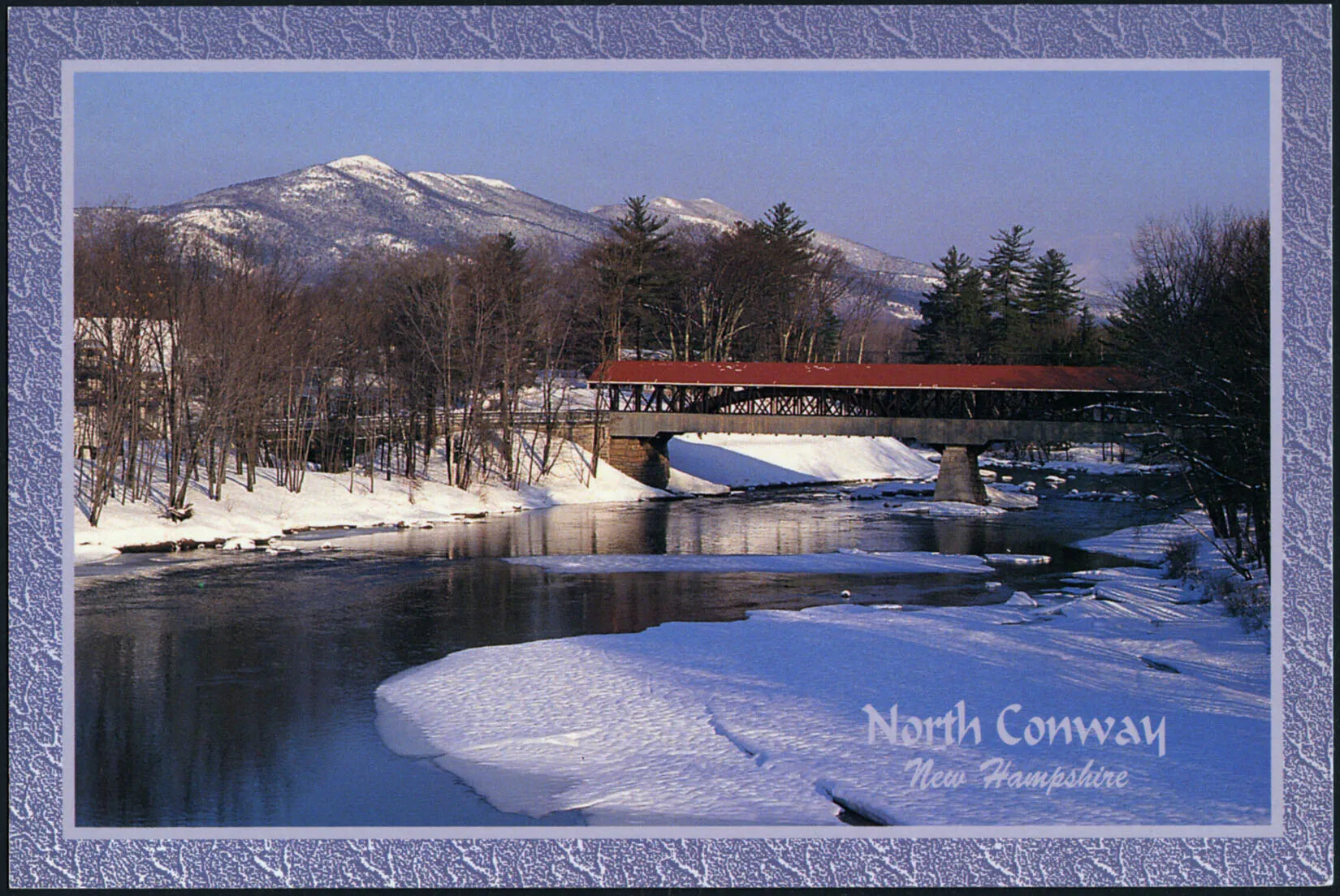 A colored horizontal postcard of a long body of water, a covered bridge with a red roof, and a snow-covered background in hthe background. The land on either side of the body of water is covered with bare trees and snow-covered ground. The title of the postcard, placed in the lower right-hand corner, reads "North Conway/New Hampshire."