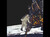In a color photograph, an astronaut with a white spacesuit and large backpack descends a ladder. He is leaving a small spaceship and stepping down to walk on the moon. 