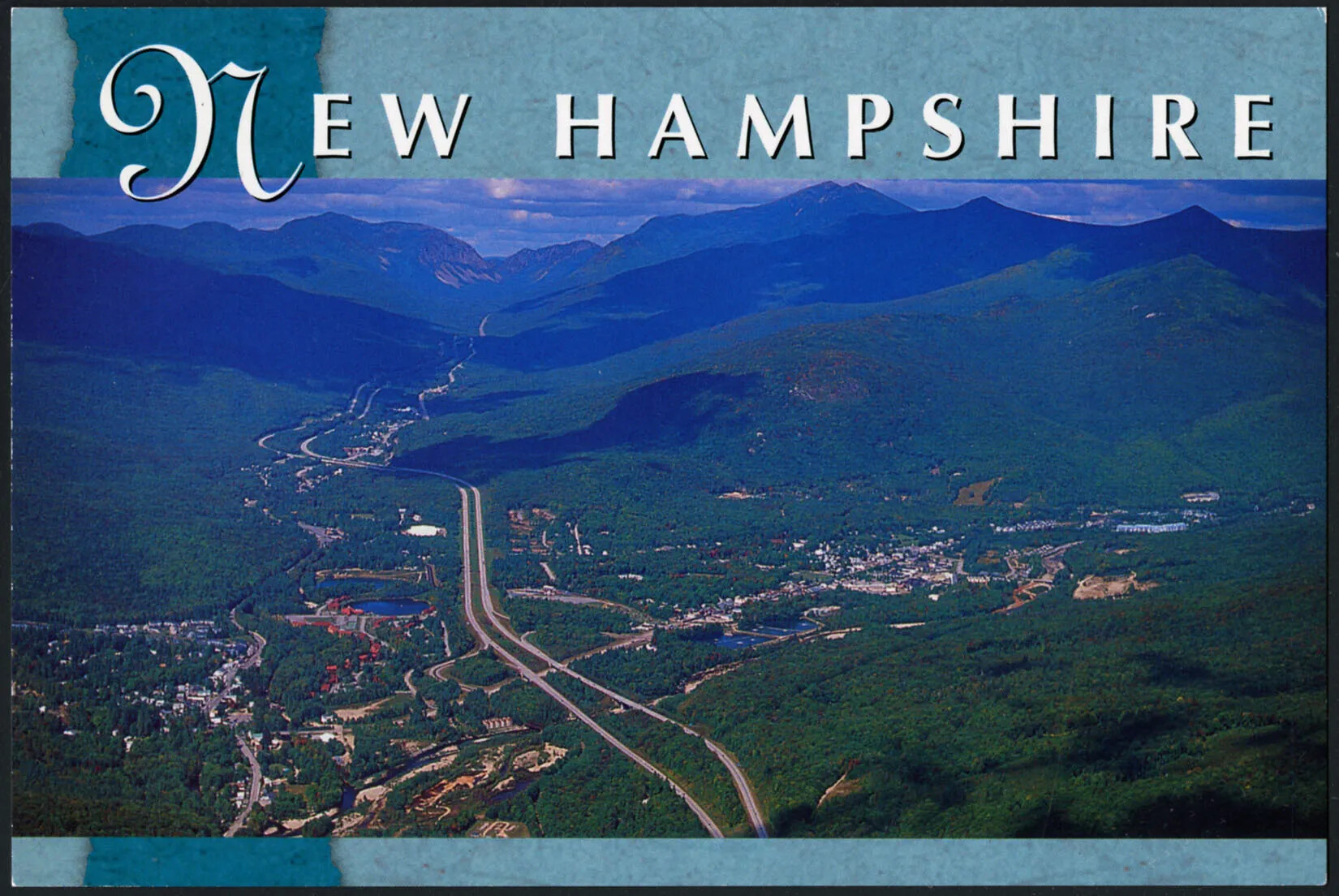 A colored horizontal postcard of a bird's-eye view of a road which stretches down the middle of a valley. The valley is surrounded by two ranges of green mountains. On either side of the road are towns with several buildings and small roads. The title of the postcard, centered along the upper border of the postcard, reads "NEW HAMPSHIRE."