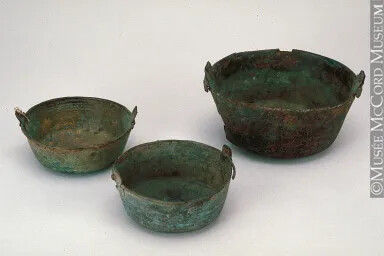 Three metal pots, one large and two medium-sized. All of the pots have raised edges to accommodate a rounded handle.
