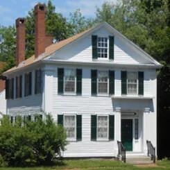 White historic house with green shutters and twin brick chimneys, known as the Pierce Manse.