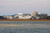 A colored photograph of several multi-storied buildings and domed buildings next to a large body of water.