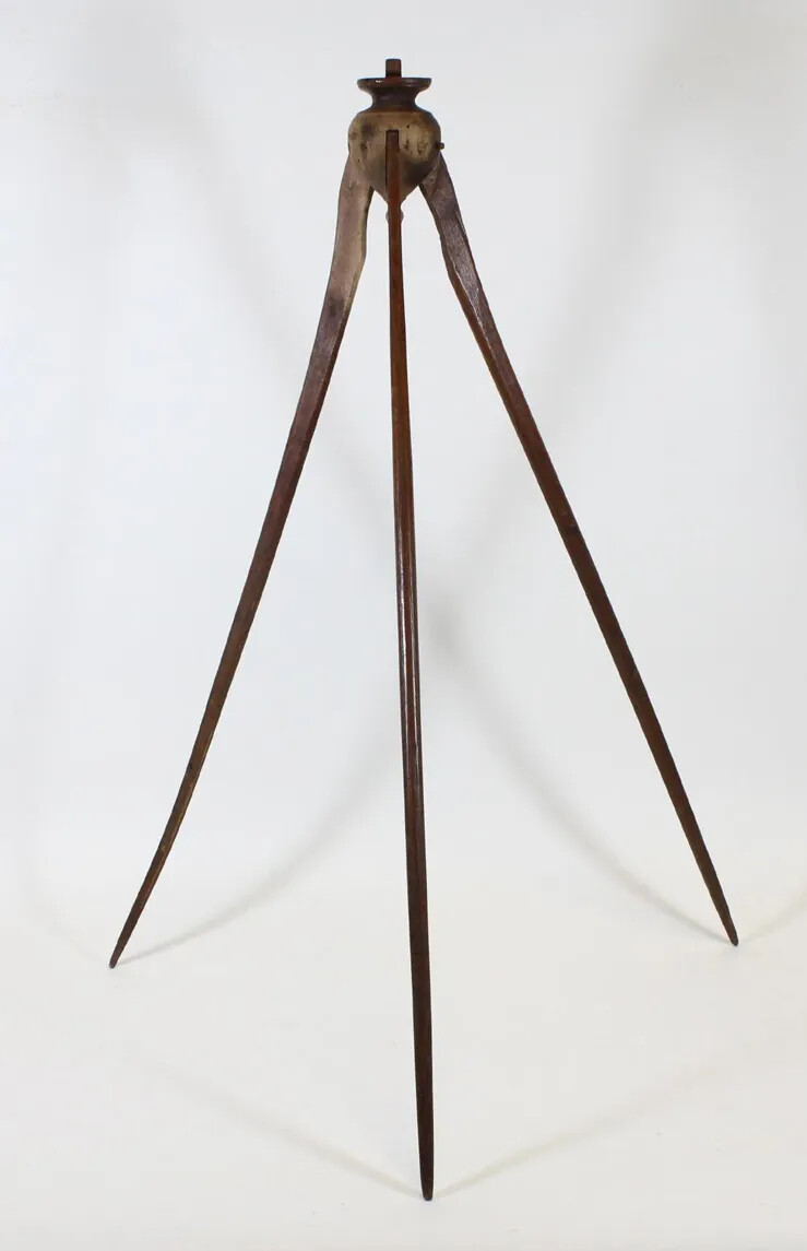 A tall wooden tripod, which stands on three pointed legs. At the top of the tool is a upside-down tear-drop shape and flat base.