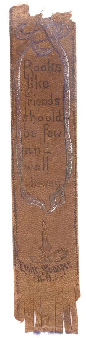 A long piece of brown leather with a tear on the top and fringe on the bottom. Written in the center are the words "Book/like/friends/should/be few/and well/chosen", handwritten in black ink. Drawn beneath is a candle and thin lines of smoke that go up the sides of the piece of leather and frame those words. Beneath the candle are the words "Lake Sunapee/N.H." handwritten in black ink.