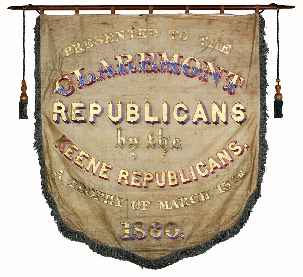 A cloth banner that hangs from a wooden rod. Painted writing on the banner reads "PRESENTED TO THE/CLAREMONT/REPUBLICATION/by the/KEENE REPUBLICANS./A TROPHY OF MARCH 15TH/1860."