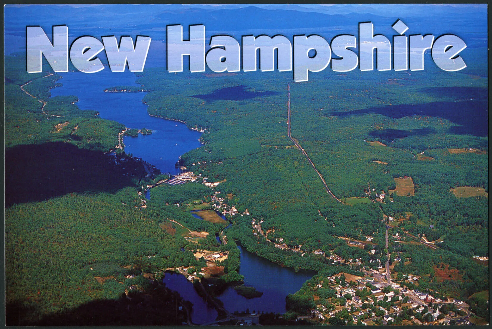 A colored horizontal postcard of an bird's-eye view of a large, flat green area, which is split by two long bodies of water. In the bottom right-hand corner is a town with lots of buildings and roads. The title of the postcard, which is centered along the upper border reads "New Hampshire."