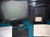A color photograph of a black computer monitor is seen. It sits on a blue desk with part of a keyboard, covered by a piece of paper with typing, visible below. On the keyboard reads "PROPRIETE CERN." 