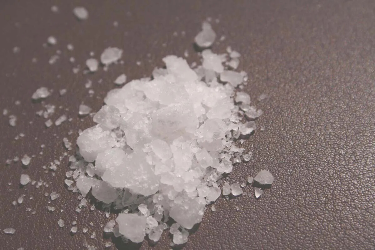 A pile of large and small white crystals on a gray table.