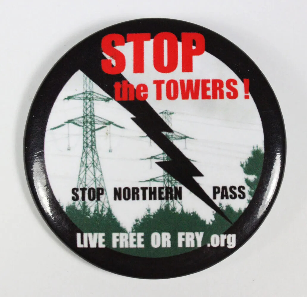 A circular button outlined in black. Diagonally across the button is a black lightning icon. Text typed onto the button read, from top to bottom: "STOP/the TOWERS!" in red text, "STOP NORTHERN PASS" in black text, and "LIVE FREE OR FRY .org" in white text.