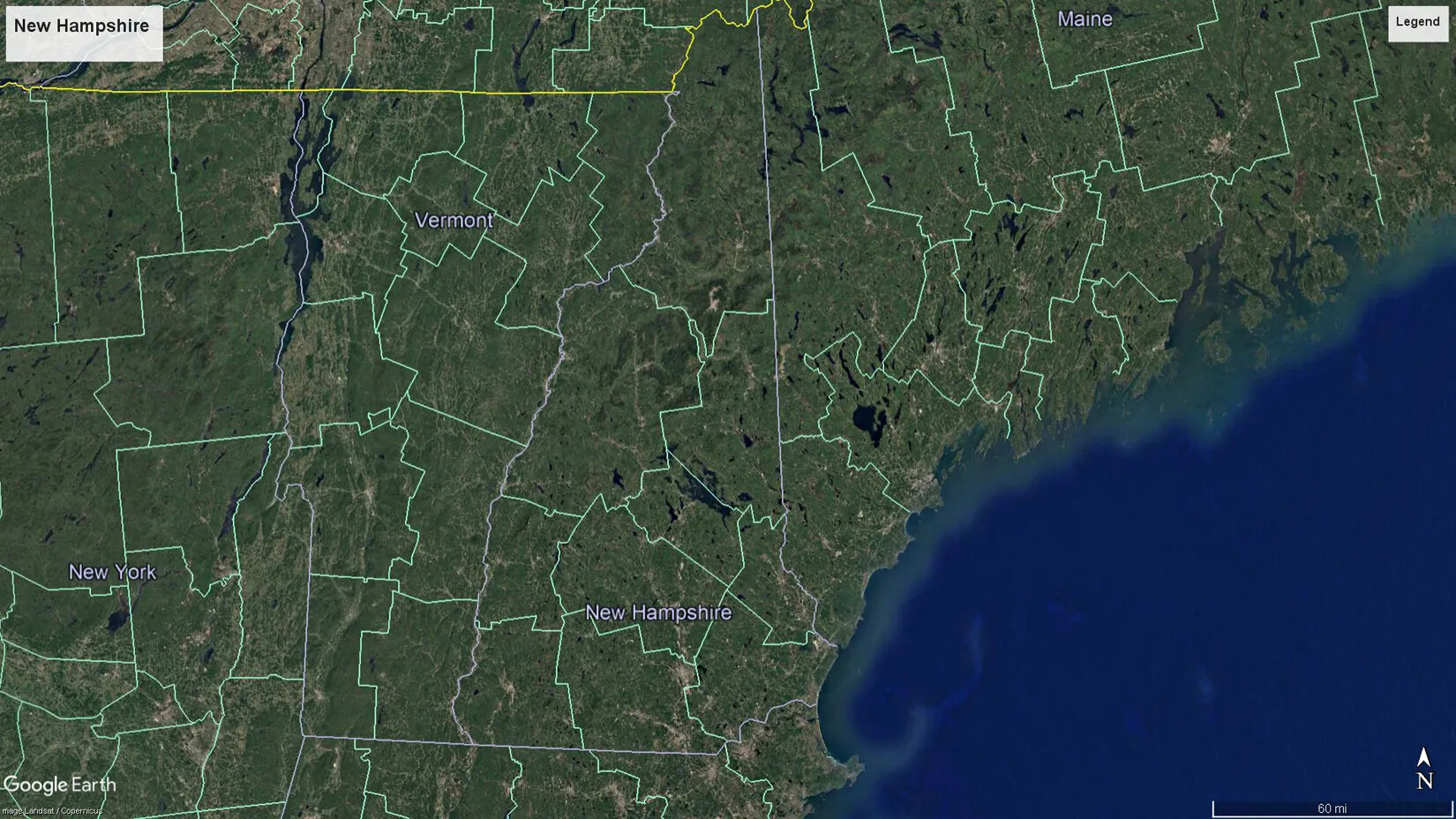 A colored close-up screenshot of Maine, New Hampshire, Vermont, and New York from Google Earth. The land masses are green and the Atlantic Ocean is blue. The states are segmented into large county borders, outlined in light green.