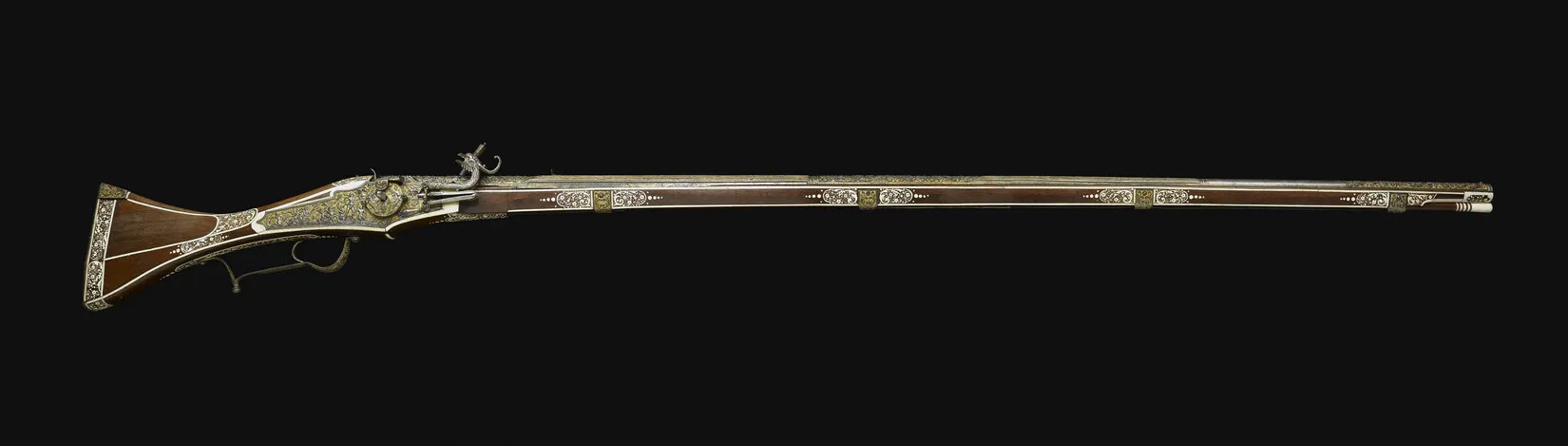 A brown musket with a long barrel and decorated handle.