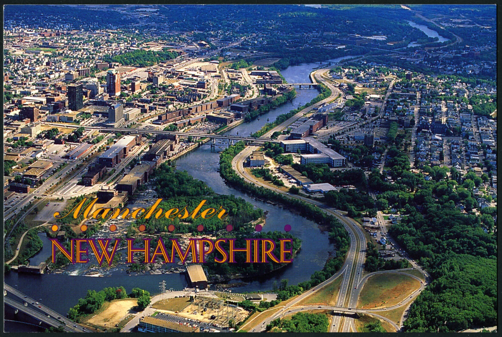 A colored horizontal postcard of a city along a river. The river passes through two sides of the city. To the river's left are lots of tall buildings, and to its right are vertical rows of houses and smaller buildings. The title of the postcard, placed in the left-hand corner, reads "Manchester/NEW HAMPSHIRE."
